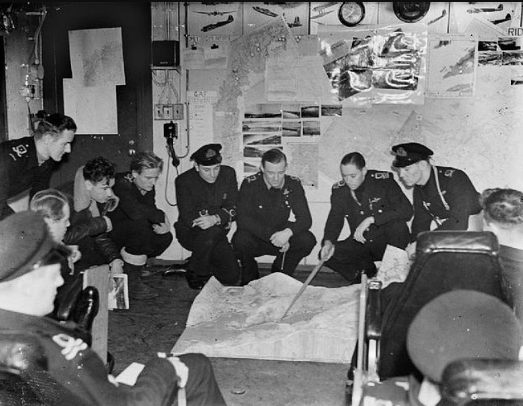 Fighter pilots in the briefing room of HMS PURSUER check over the details of their next operation with their Squadron Leader Lieutenant Commander Hordern. 